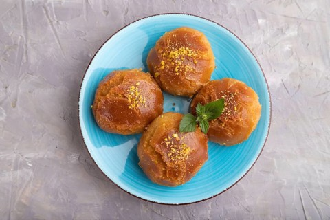 Homemade traditional turkish dessert sekerpare with almonds and honey on gray concrete background.