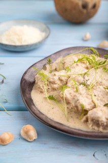 Stewed chicken fillets with coconut milk sauce and mizuna cabbage microgreen on blue wooden