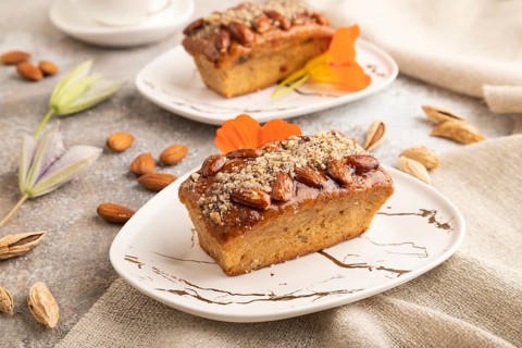 Caramel and almond cake with cup of coffee on brown concrete background and linen textile. side
