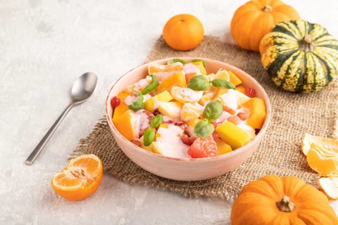 Vegetarian fruit salad of yogurt pumpkin, tangerine, pomegranate, grapefruit, basil microgreen