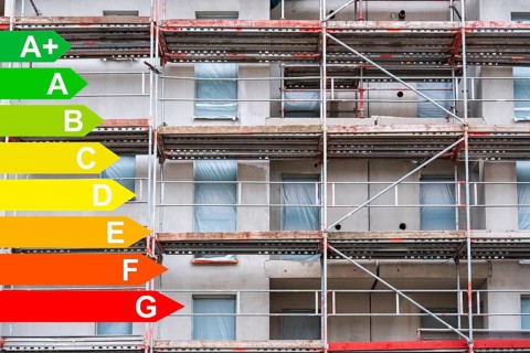 Scaffolding at the construction site of a new housing estate, graphic with energy efficiency