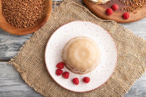 Buckwheat milk jelly on gray wooden background and linen textile. top view, flat lay