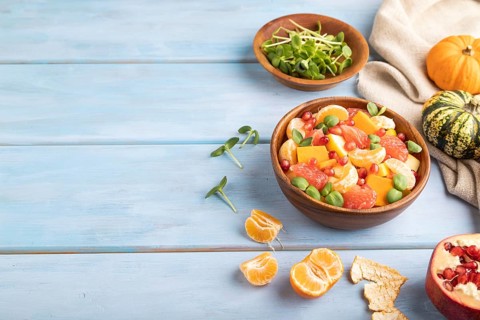 Vegetarian fruit salad of pumpkin, tangerine, pomegranate, grapefruit, sunflower microgreen sprouts