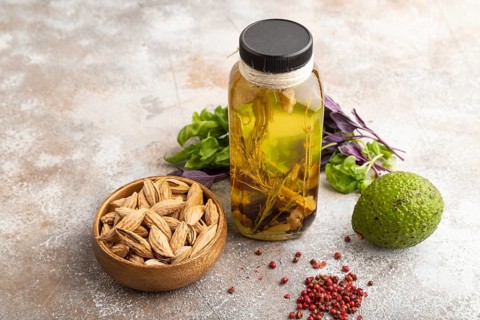 Sunflower oil in a glass jar with various herbs and spices, sesame, rosemary, avocado, basil,