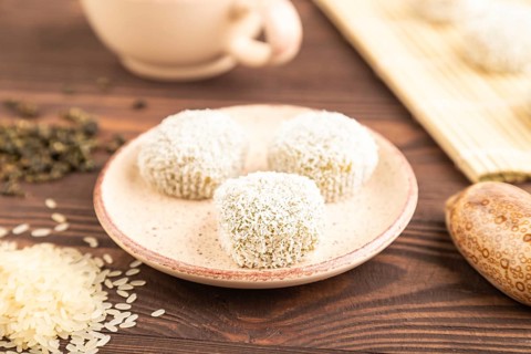 Japanese rice sweet buns mochi filled with pandan and coconut jam and cup of green tea on brown
