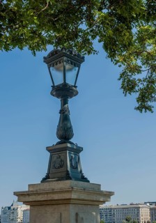 Ornate vintage street lamp against a clear blue sky in a city setting