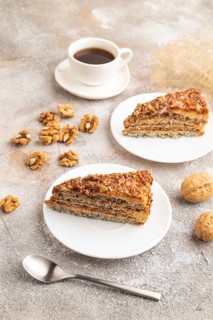 Walnut and hazelnut cake with caramel cream, cup of coffee on brown concrete background. side view