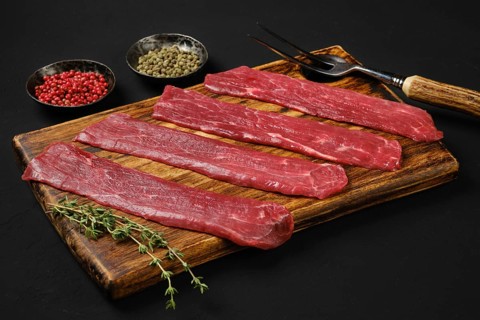 Raw beef strips on black background