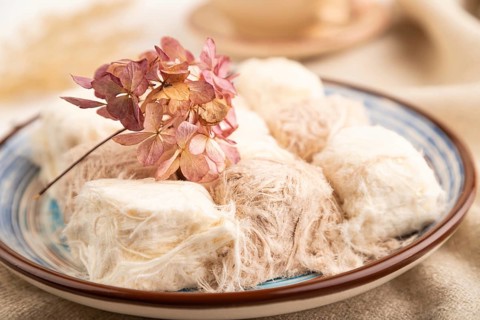 Traditional arabic sweets pishmanie and a cup of green tea on white wooden background and linen