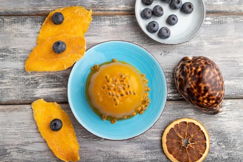 Mango and passion fruit jelly with blueberry on gray wooden background. top view, flat lay, close