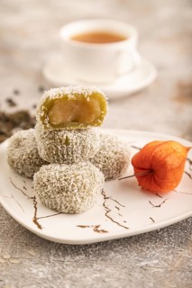 Japanese rice sweet buns mochi filled with pandan jam and cup of green tea on brown concrete