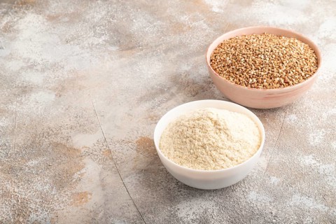 Powdered milk and buckwheat baby food mix, infant formula on brown concrete background. Side view,