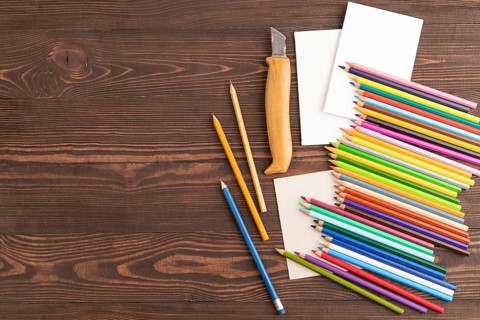 Set of watercolor pencils on brown wooden background. Top view, flat lay, copy space