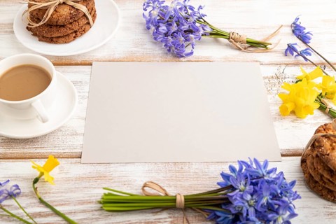 Gray paper sheet with oatmeal cookies, spring snowdrop flowers bluebells, narcissus and cup of