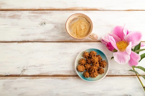 Homemade soft caramel fudge candies on blue plate and cup of coffee on white wooden background,