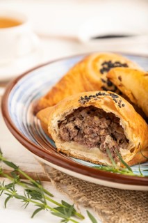 Homemade asian pastry samosa, cup of green tea on white wooden background and linen textile. side
