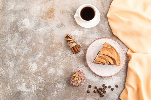 Zephyr or marshmallow cake with cup of coffee on brown concrete background and orange textile. top