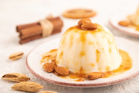White milk jelly with caramel sauce on gray concrete background. side view, close up, selective