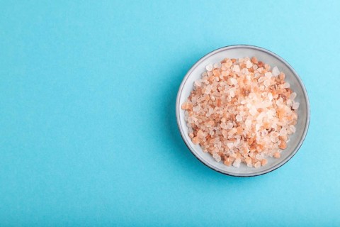 Plate with pink Himalayan salt on blue pastel background. top view, flat lay, copy space