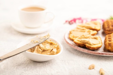 Homemade waffle with peanut butter and cup of coffee on a gray concrete background. side view,