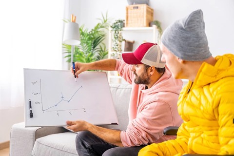 Disabled man learning economy from home with a particular teacher that uses a white board to draw a