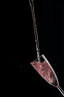 A champagne glass catches rose sparkling wine against a dark background