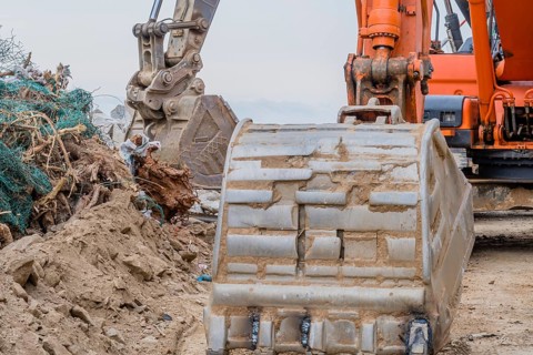 Closeup of bucked on backhoe parked at rural construction site on overcast day