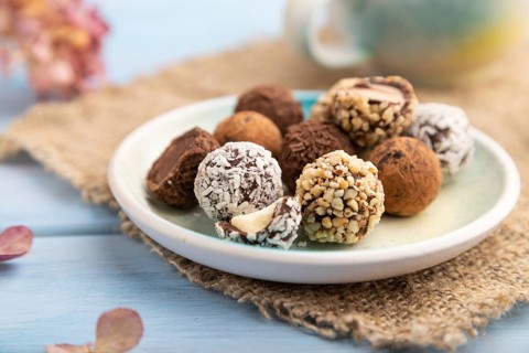 Chocolate truffle candies with cup of coffee on a blue wooden background and linen textile. side