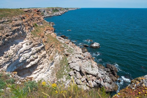 A steep cliff on a quiet coast with a view of the blue sea and clear sky, cliff, Kamen Bryag,