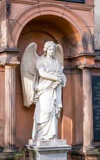 White angel statue with folded arms and spread wings in front of an arch, White, female angel