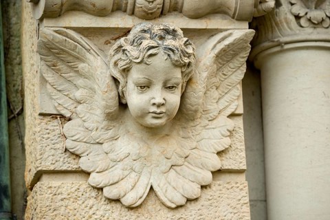 Historic stone angel figure, angel figure, angel with lowered gaze and detailed wings on a column,