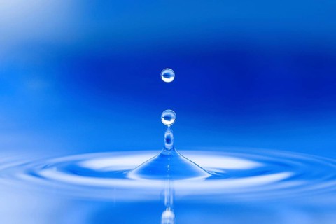 Water droplets jump up from the blue water surface