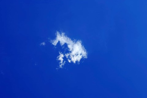 A single young small fluffy white fair weather cloud, Cumulus humilis, just forming in the blue sky