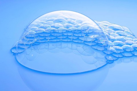 One large and many small soap bubbles on light blue water