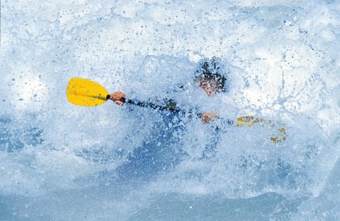 A kayaker almost goes under in a wave in the Isar at the Wittelsbacherbrücke, Munich, Bavaria,