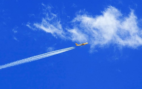 A passenger plane of the insolvent travel company Thomas Cook with vapour trails in the blue sky