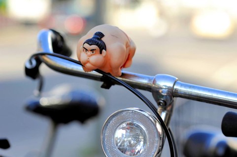 A sumo wrestler attached to the handlebars of a bicycle as a bicycle horn or bell