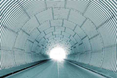 Interior view of a tunnel with bright tunnel exit, light at the end of the tunnel