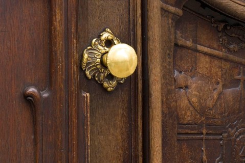 Worn brass doorknob on a dark wooden door of the Asamkirche, Sendlinger Straße, Munich, Bavaria,