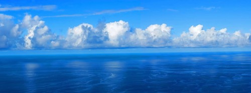View over the blue Atlantic Ocean with white clouds, panoramic shot, from the mountain slopes near