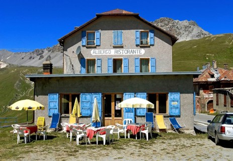 An empty, faded Albergo restaurant near the top of the Stelvio Pass with parasols and tables