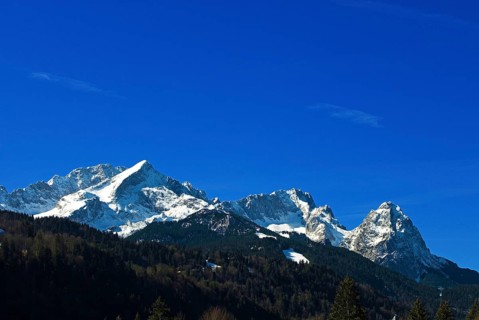 Mountain panorama of the snow-covered Wetterstein mountains in spring, with Alpspitze on the left,