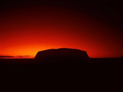 Silhouette outline of Ayers Rock or Uluru in red sunrise or sunset, dusk or dawn, red sky, Northern