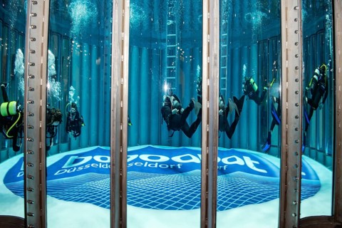 Close-up of several divers in the water in diving tower of Messe boot, on the ground lettering Log