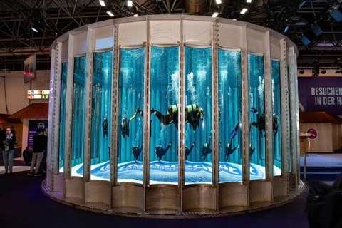 Complete view frontal long shot of several divers in the water in circular diving tower of Messe