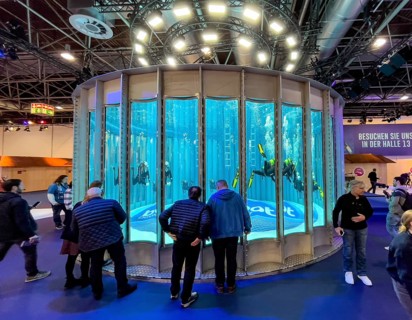 Full frontal view long shot of several divers in the water in a circular diving tower at the boot