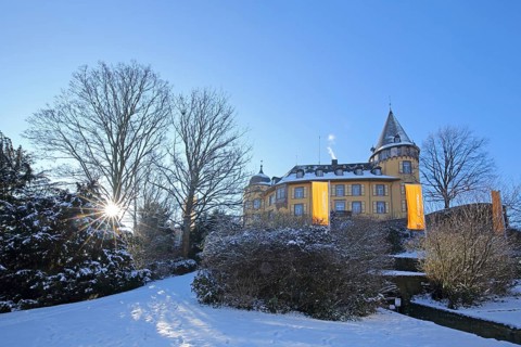 Landmark Genoveva Castle built in the 13th century backlit in winter and flags Eifelmuseum,