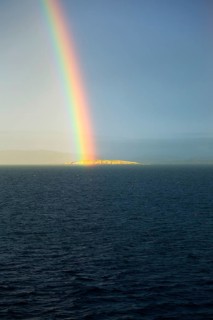 Seascape view of spectrum colours in rainbow over sea and island, Norway, Europe