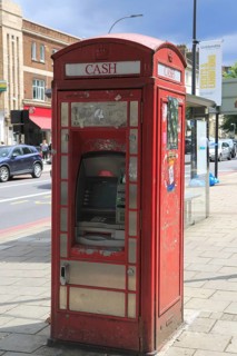 Traditional red telephone kiosk converted to ATM cash machine, New Cross, Deptford, south London,