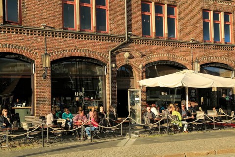 People sitting in sunshine outside cafe Bryggen area, Bergen, Norway, Europe
